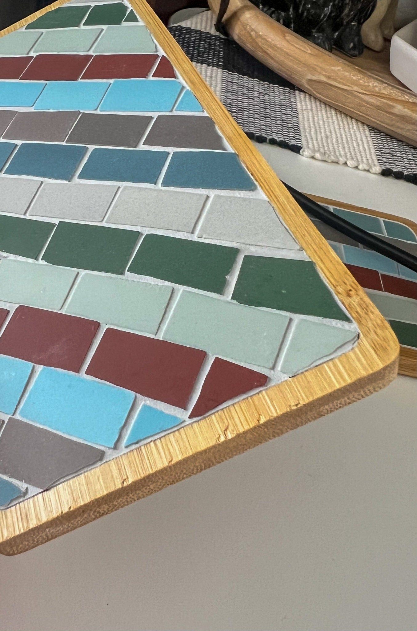 Striped rectangular mosaic coaster in deep red, blue, green, gray and ivory in a wood base with light gray grout
