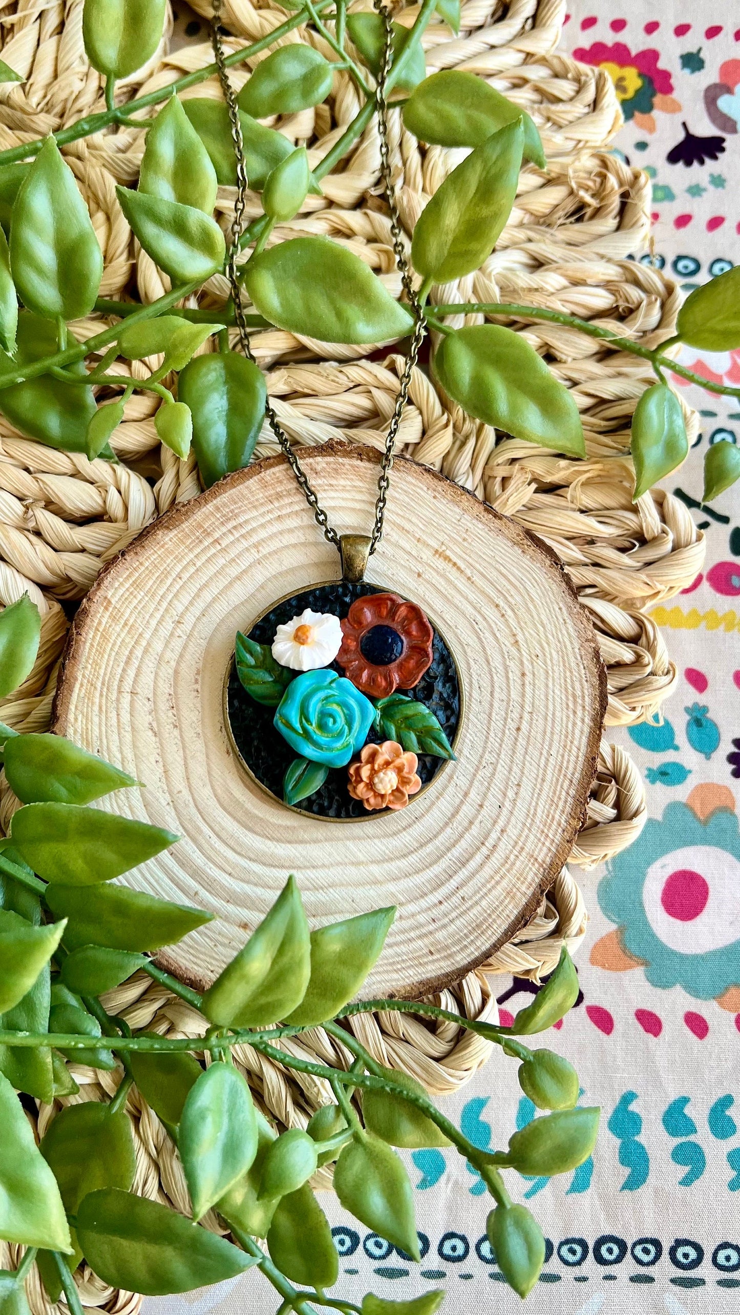 Polymer clay floral necklace in blue maroon white in a round bronze bezel