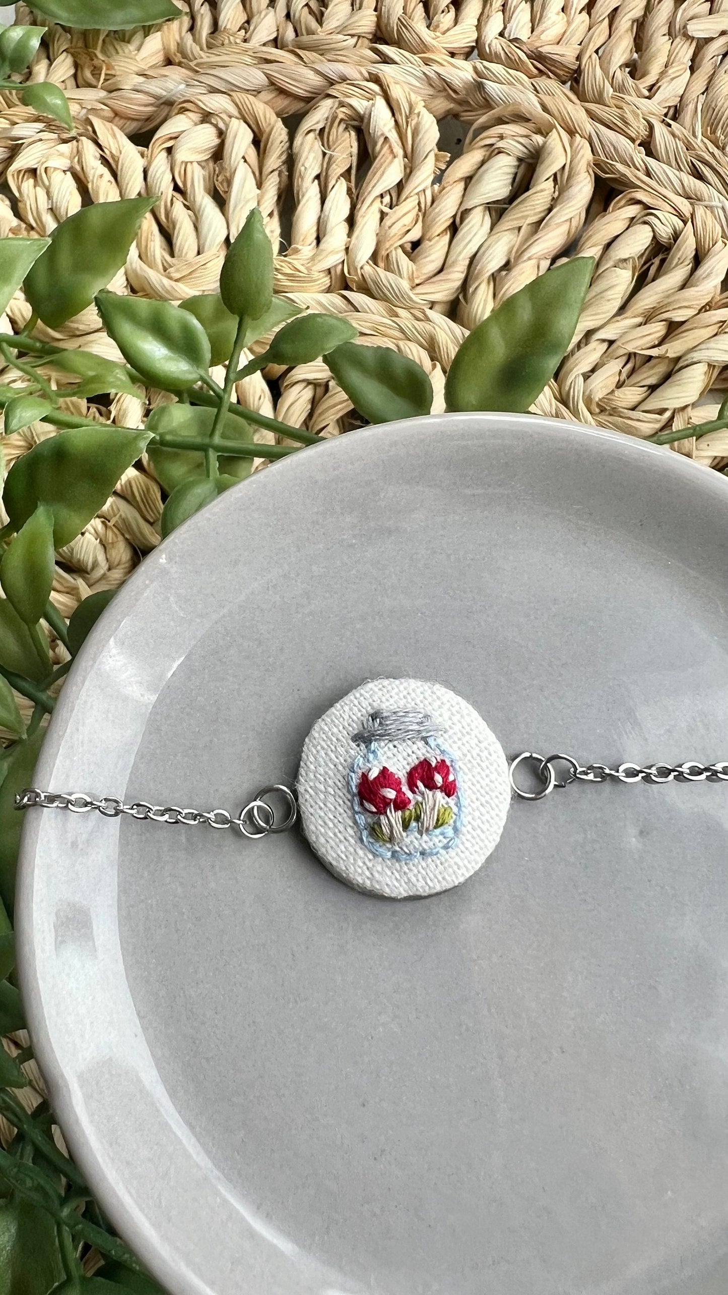 Embroidered mushroom in a jar set in a round bezel silver bracelet