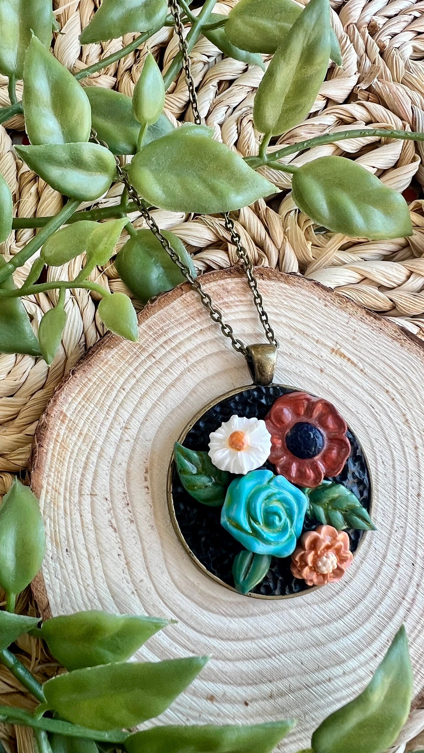 Polymer clay floral necklace in blue maroon white in a round bronze bezel