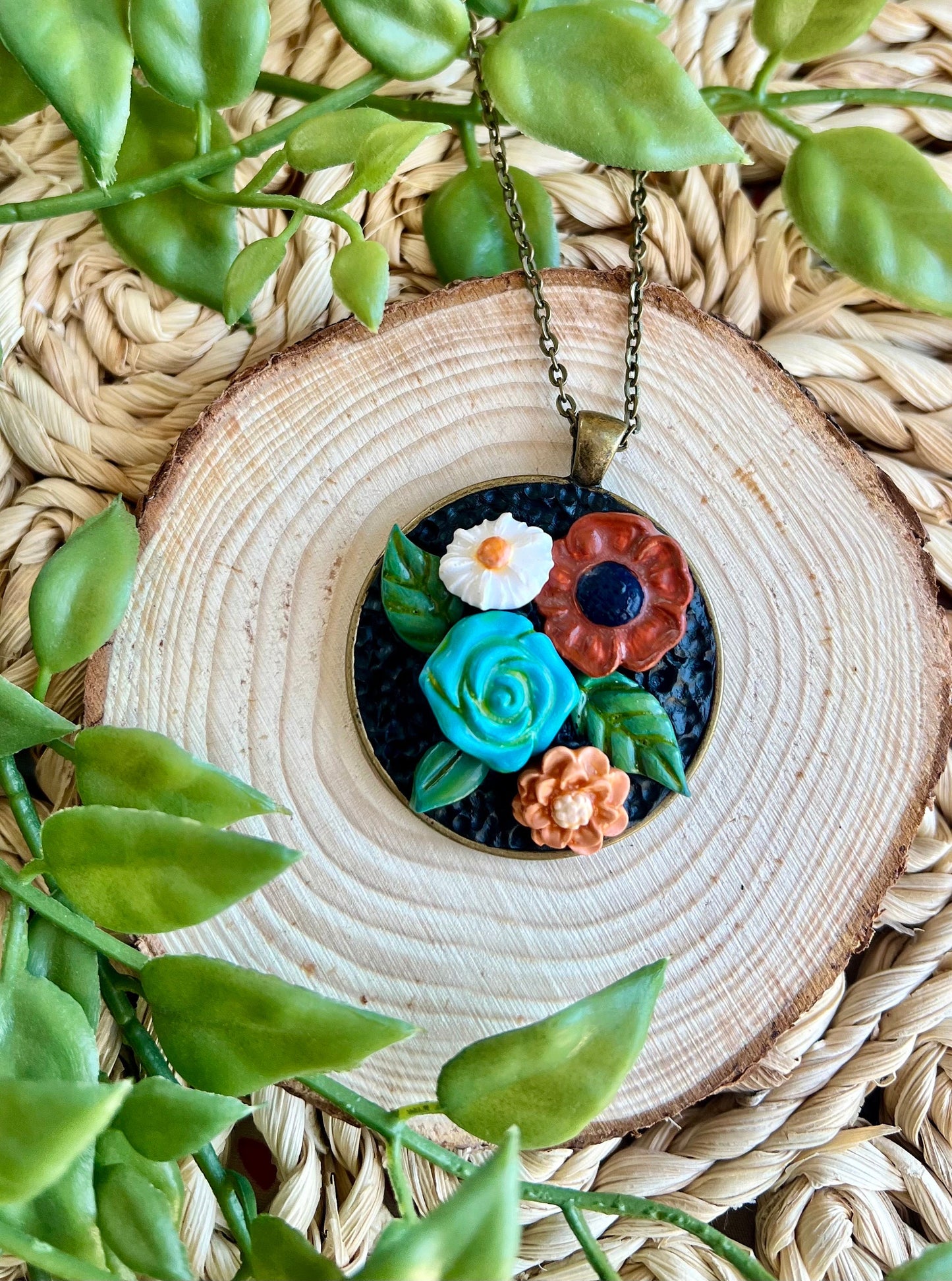 Polymer clay floral necklace in blue maroon white in a round bronze bezel
