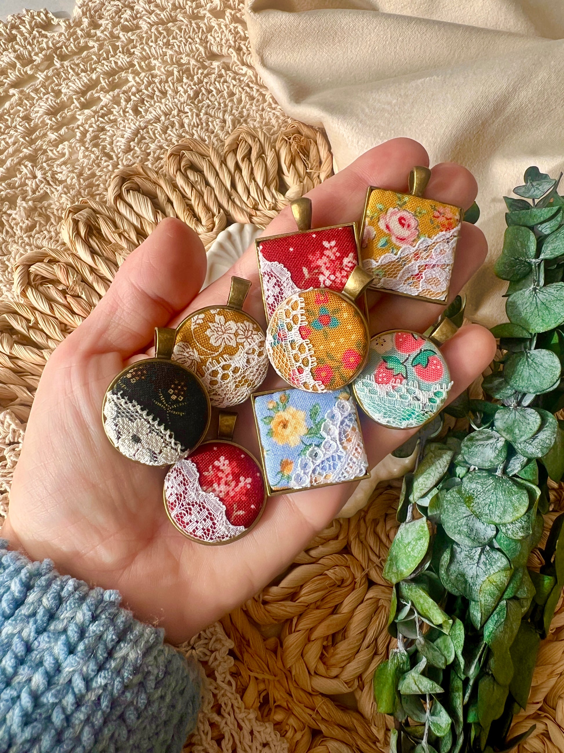 Hand holding various decorative pendants with a natural background