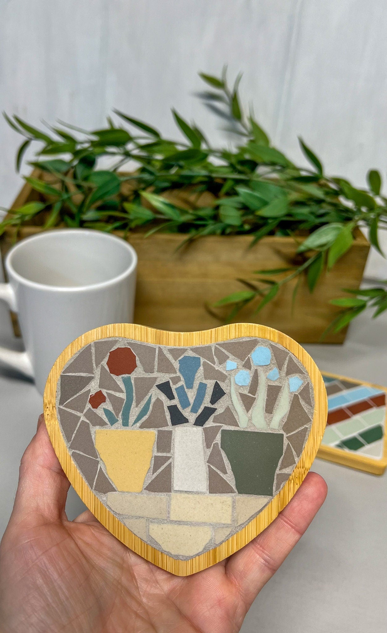 Heart shaped coaster with mosaic flowers in pots on a shelf