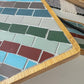 Striped rectangular mosaic coaster in deep red, blue, green, gray and ivory in a wood base with light gray grout
