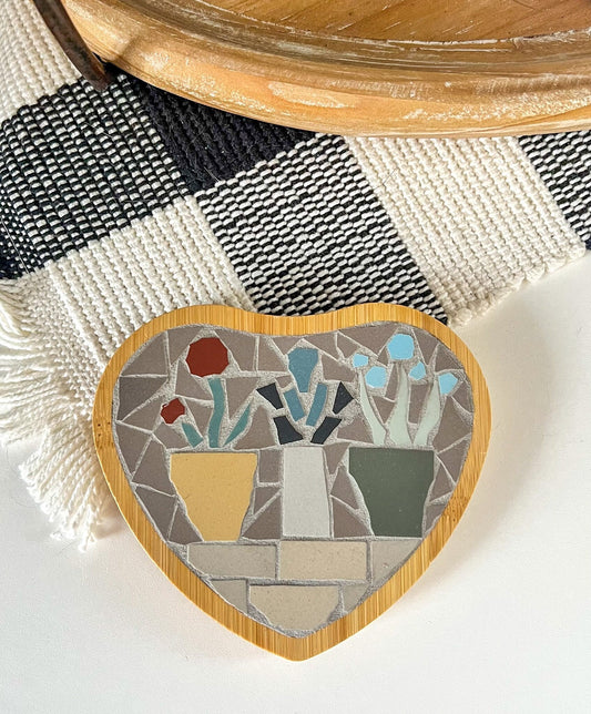 Heart shaped coaster with mosaic flowers in pots on a shelf