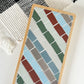 Striped rectangular mosaic coaster in deep red, blue, green, gray and ivory in a wood base with light gray grout
