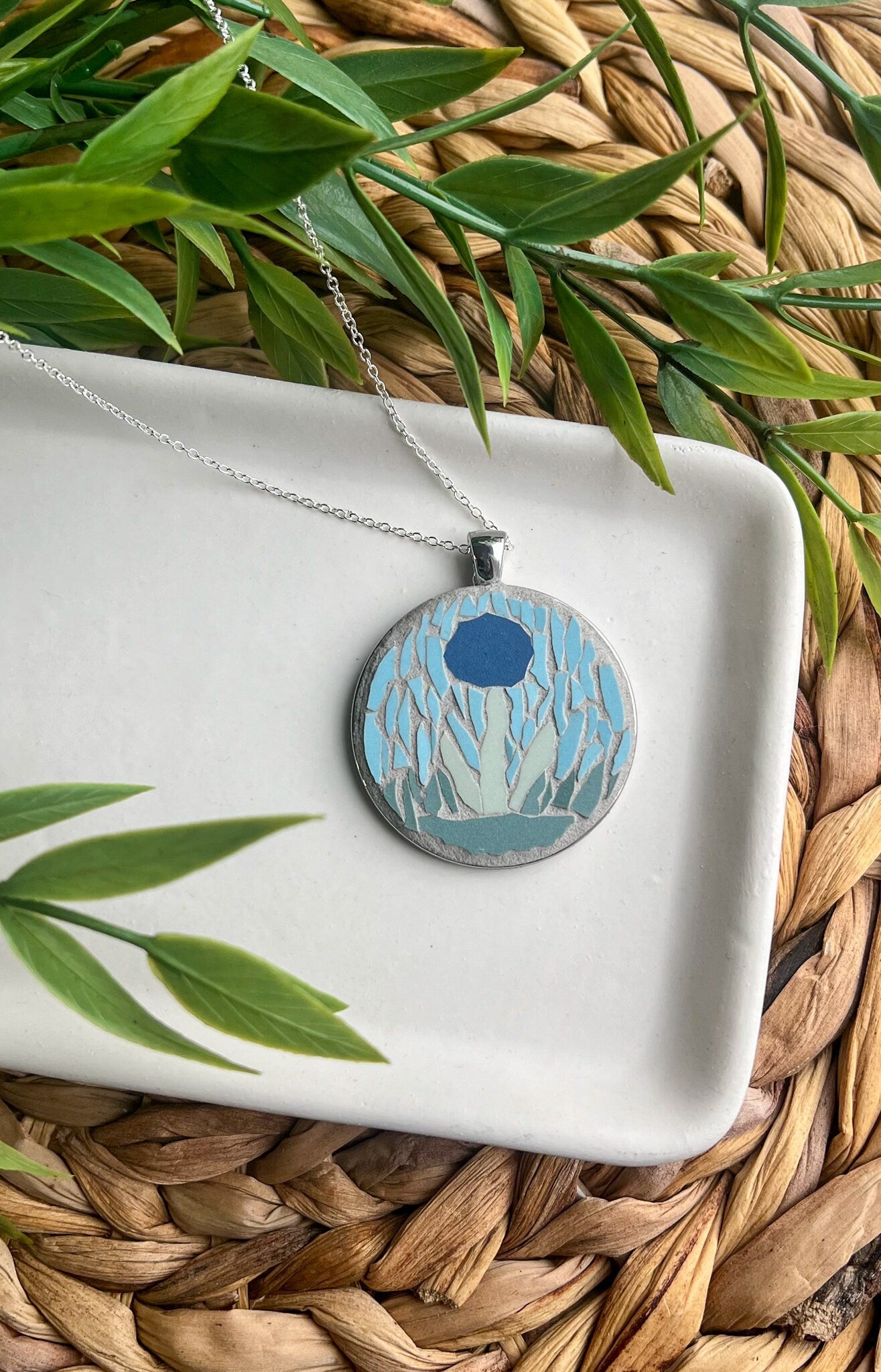 Round silver pendant with blue mosaic flower grouted in gray