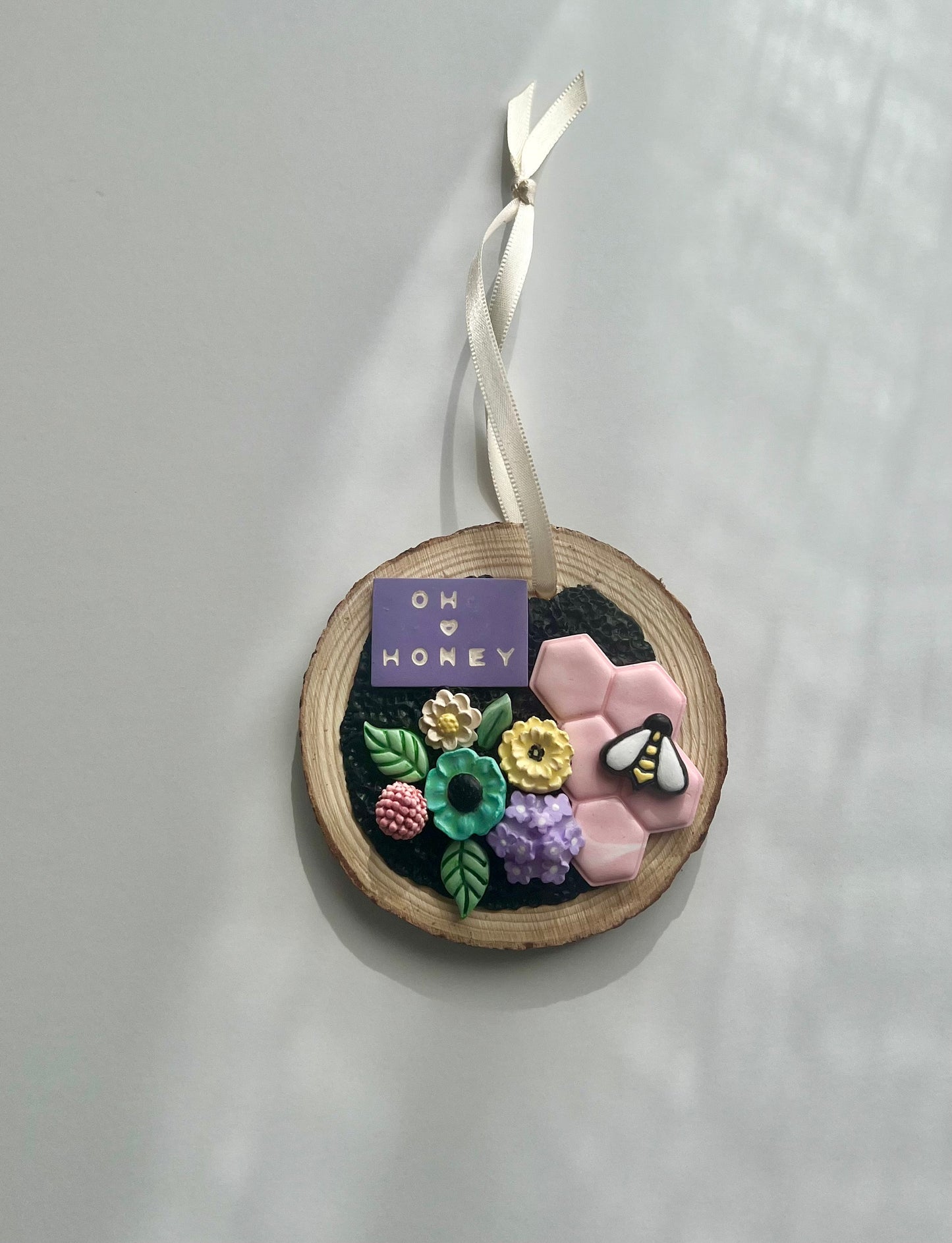 Tree slice ornament with pastel flowers pink honeycomb and bee that reads oh honey