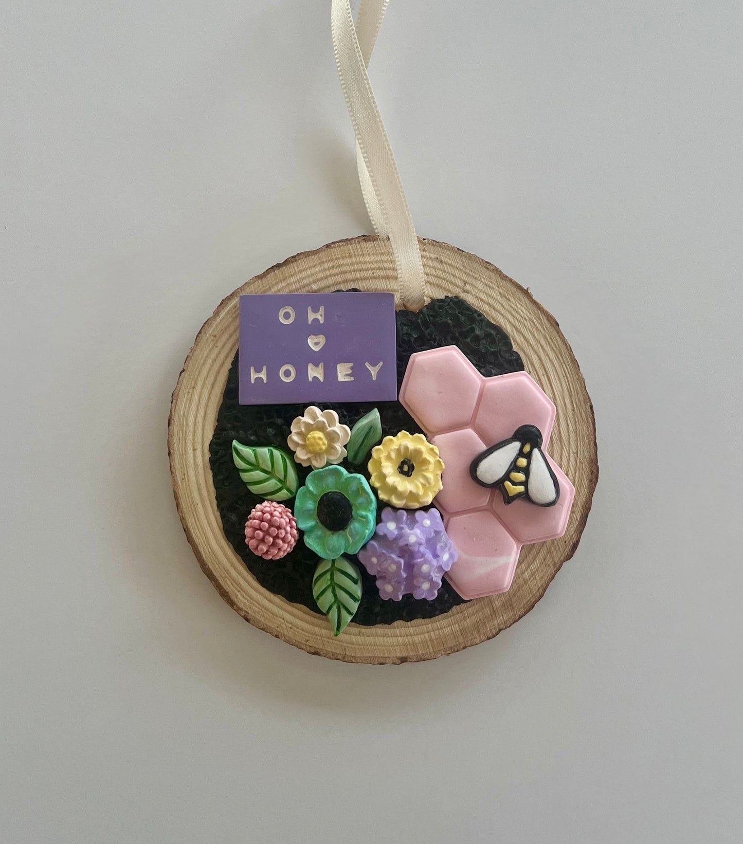 Tree slice ornament with pastel flowers pink honeycomb and bee that reads oh honey