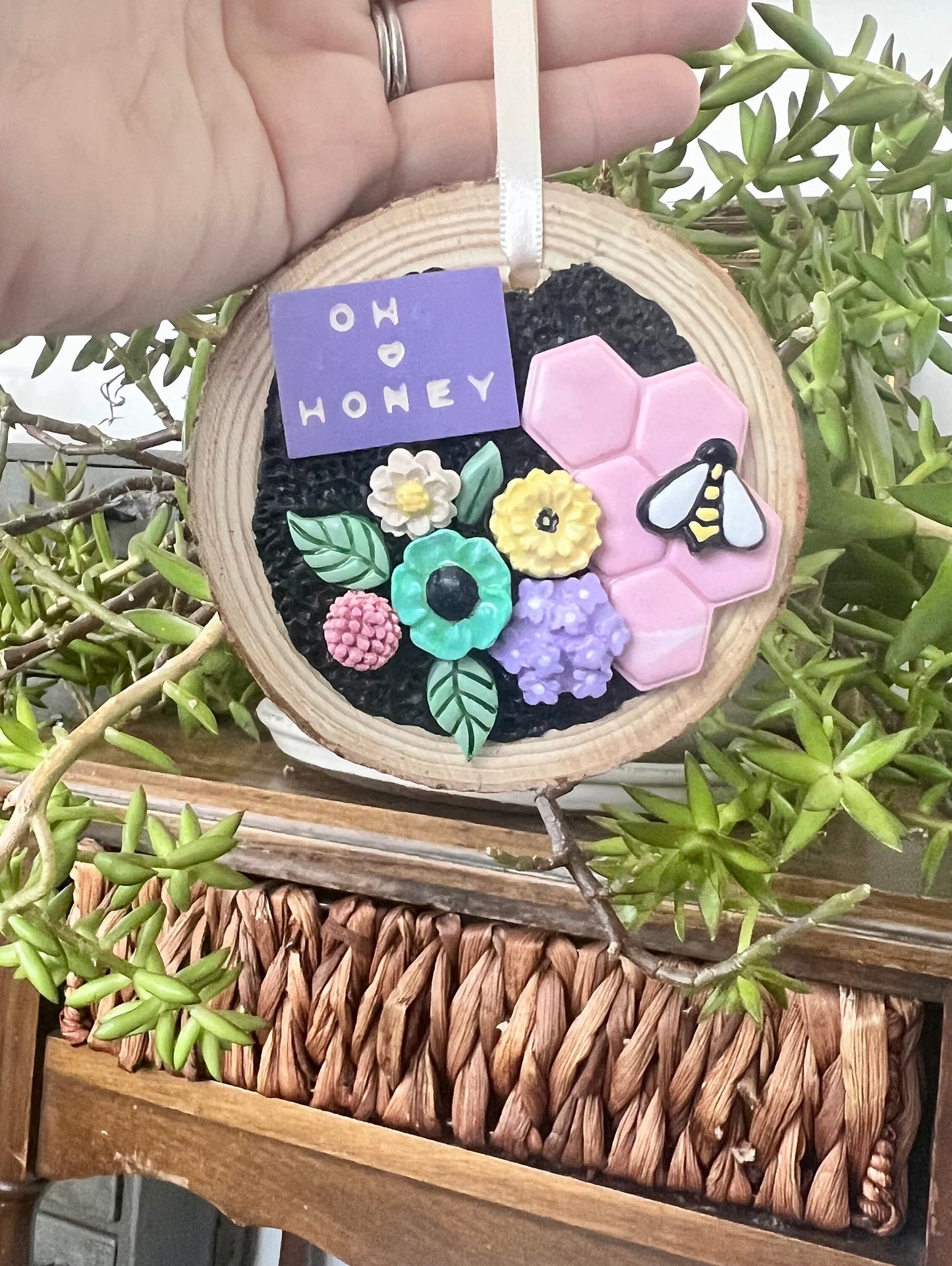 Tree slice ornament with pastel flowers pink honeycomb and bee that reads oh honey