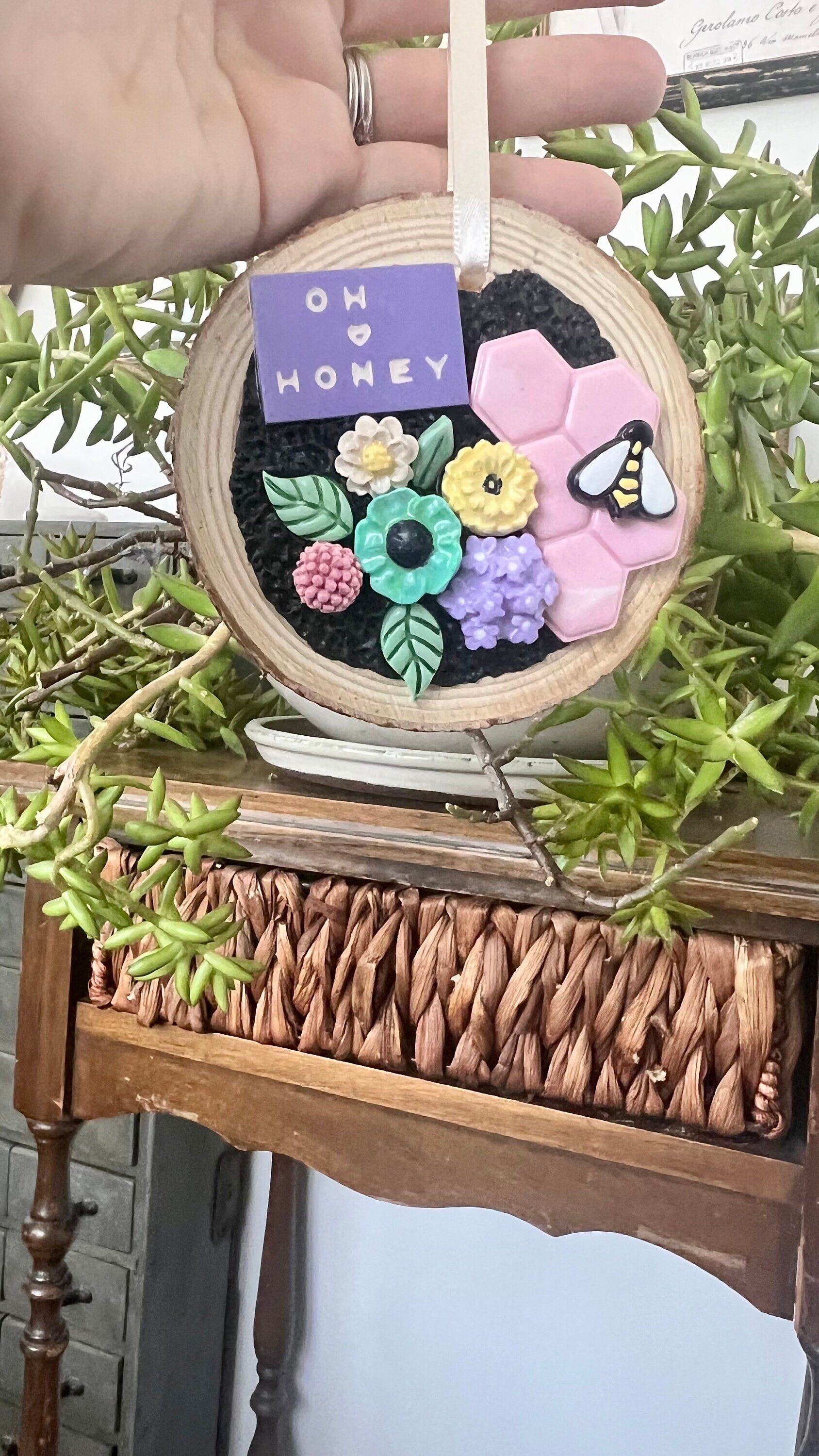 Tree slice ornament with pastel flowers pink honeycomb and bee that reads oh honey