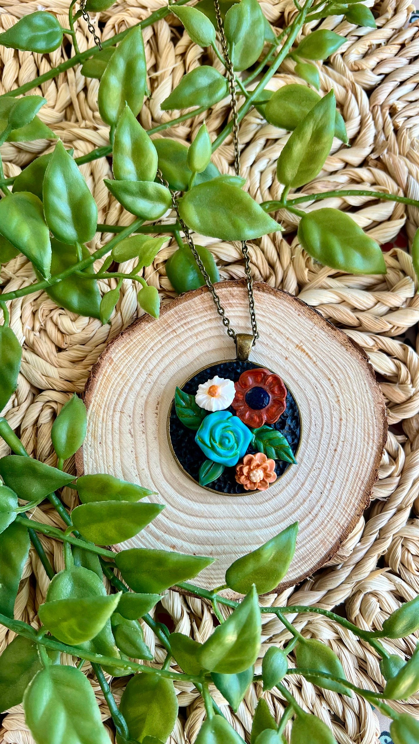 Polymer clay floral necklace in blue maroon white in a round bronze bezel