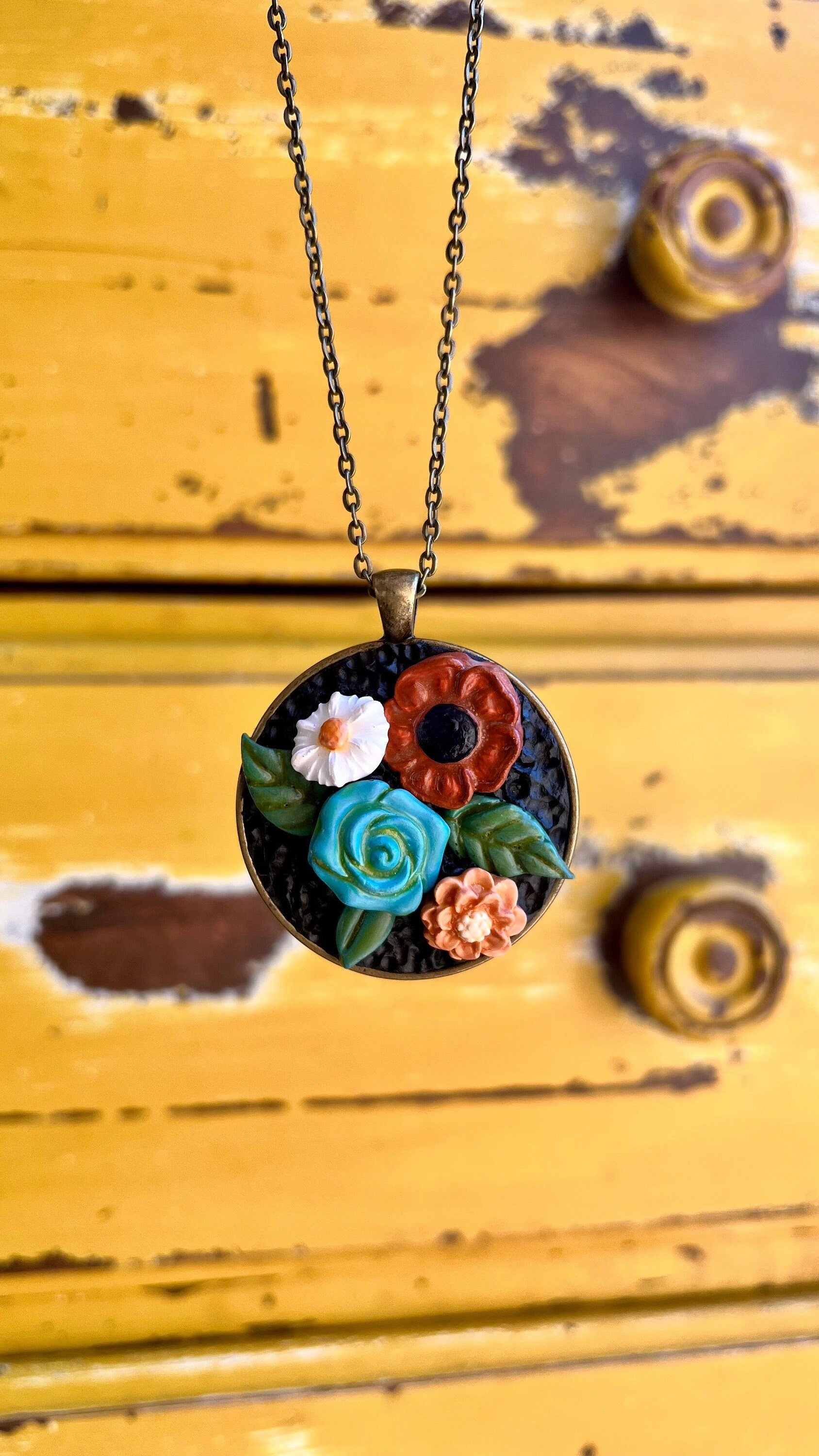 Polymer clay floral necklace in blue maroon white in a round bronze bezel