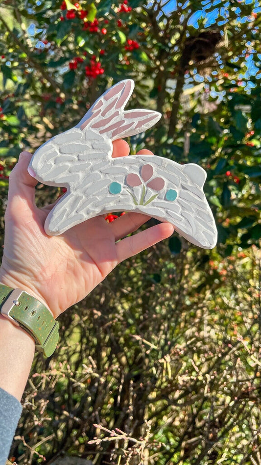 Mosaic white rabbit jumping with folk art style flowers in pink and blue