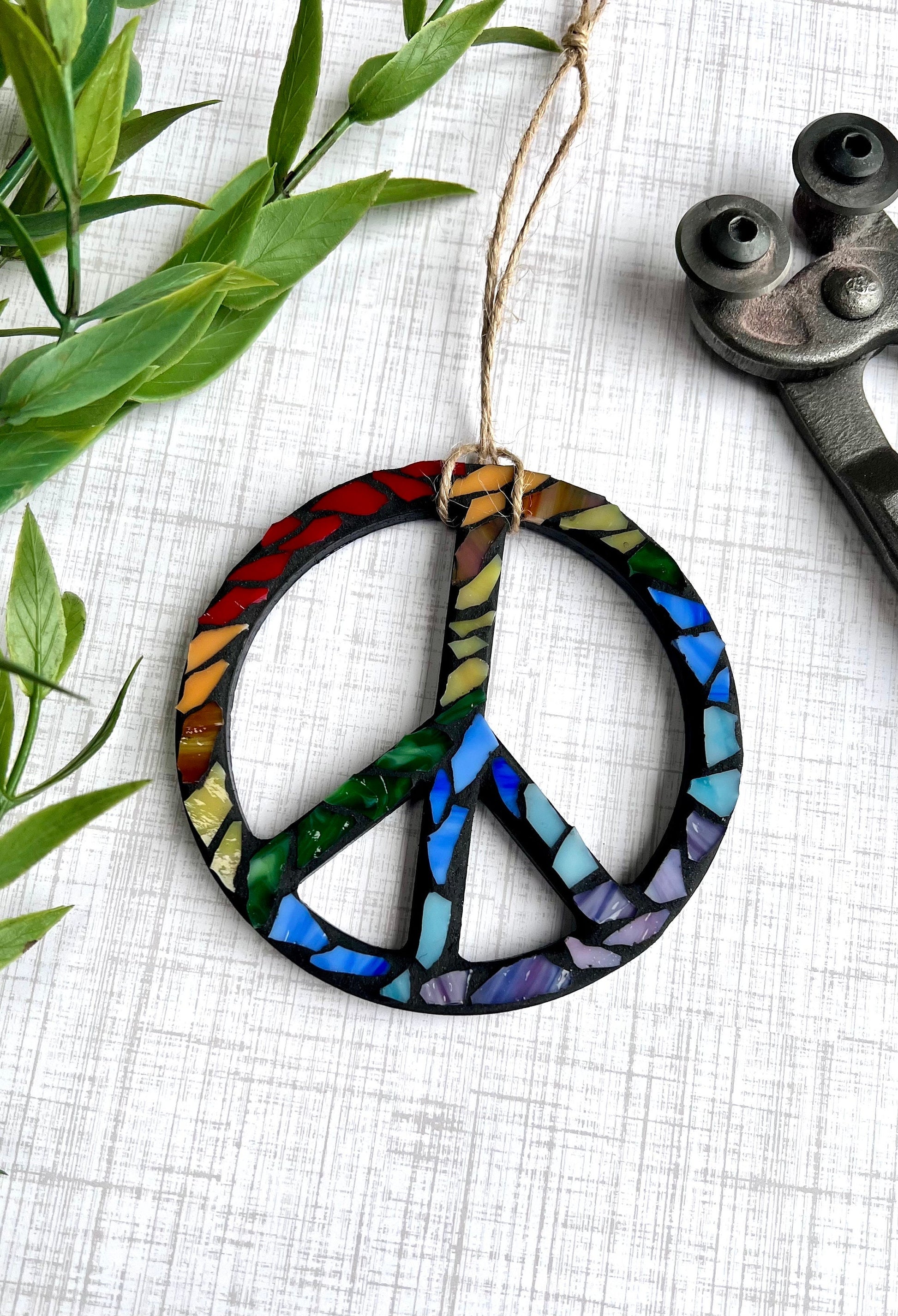 Wooden peace sign ornament with rainbow stained glass grouted in black.