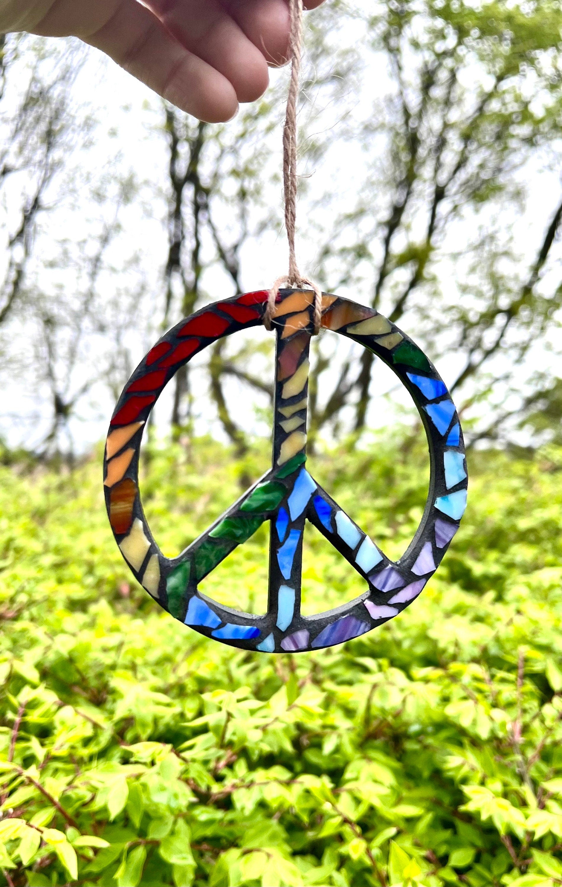 Wooden peace sign ornament with rainbow stained glass grouted in black.