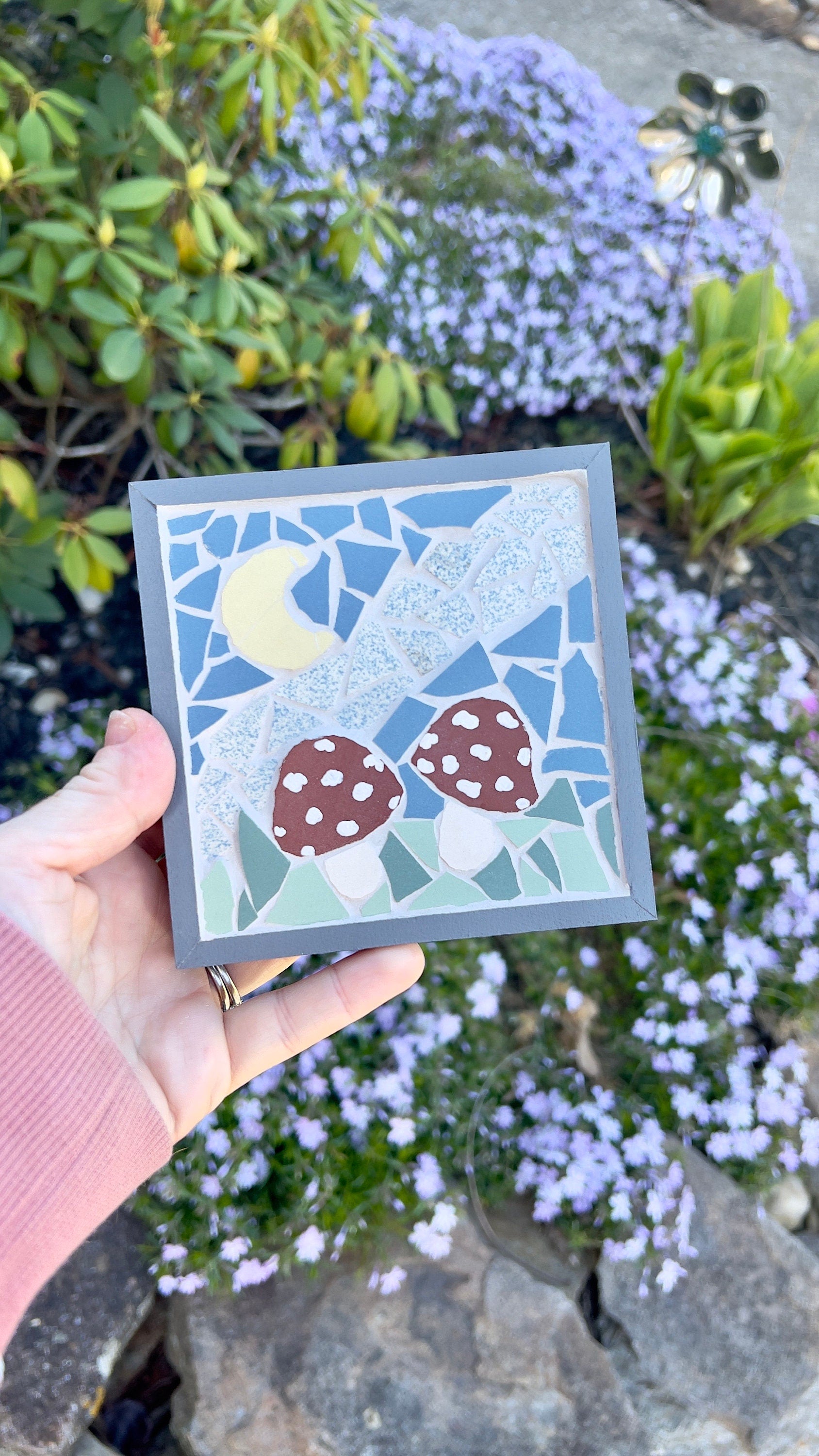 Framed mosaic art featuring two red mushrooms in a night sky with a yellow moon, framed in gray painted wood