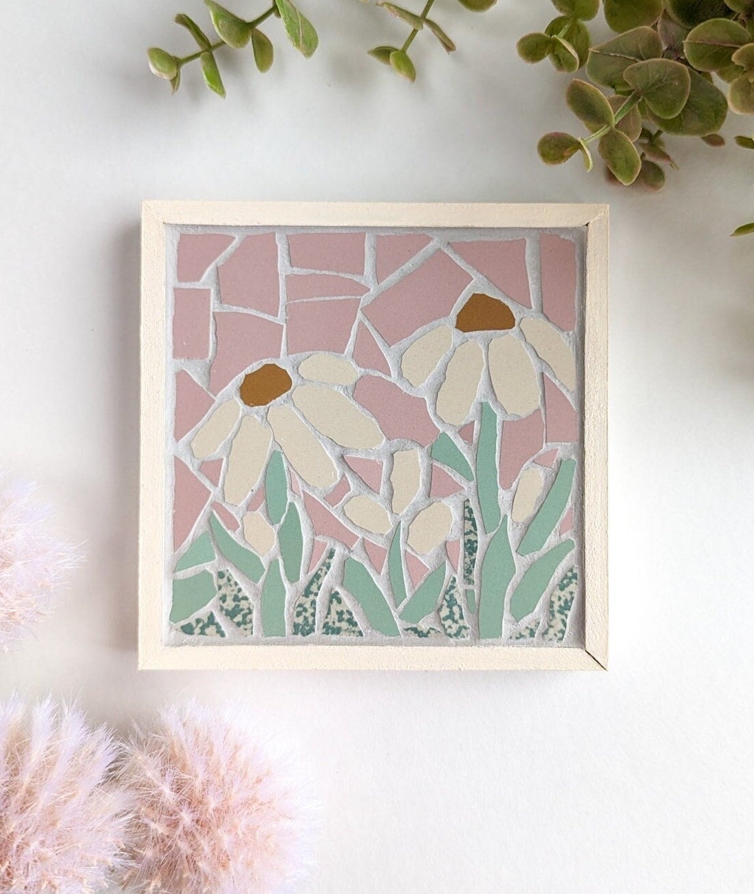 Mosaic art featuring daisies on a pink background