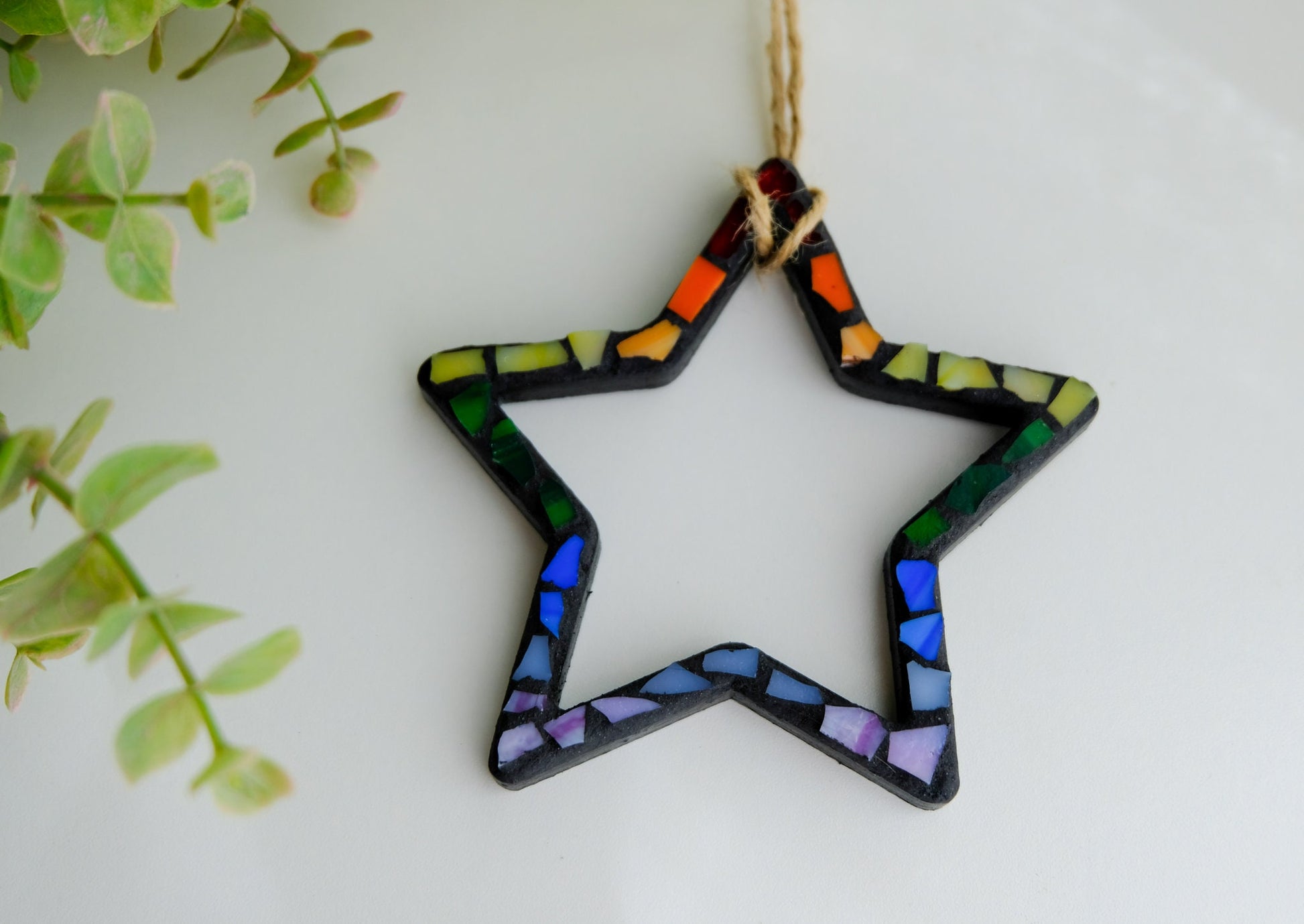 Rainbow Star stained glass mosaic ornament with black grout and a jute cord hanger